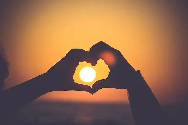 Two hands making the heart shape over the sunset